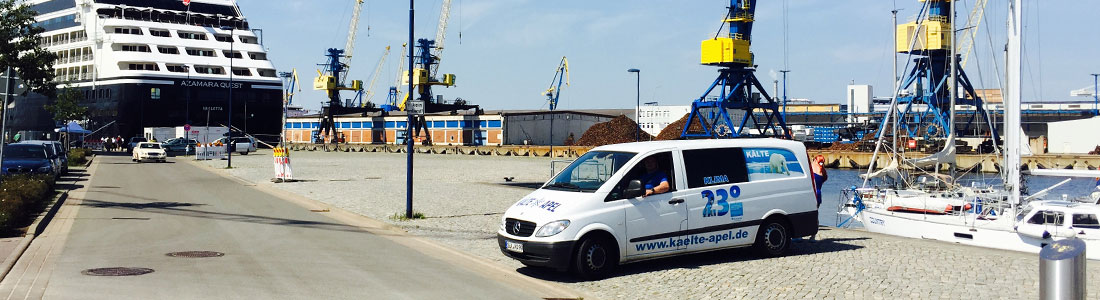 Firma Apel mit Fahrzeug in einem Hafen mit Fähre und Kränen im Hintergrund